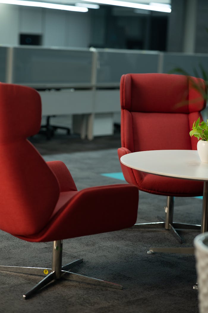 gallery-02 Contemporary office lounge featuring stylish red chairs and a round table, perfect for meetings.