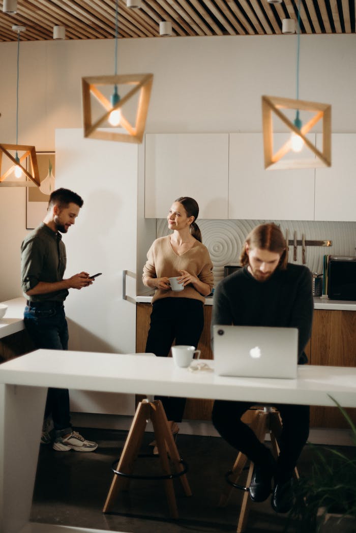gallery-03 Colleagues relaxing in a modern office break room with laptops and coffee.